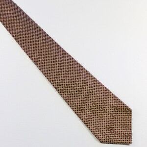 May include: A red tie with a gold and black geometric pattern.