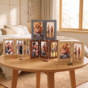 May include: A multi-panel folding picture frame set featuring various wood finishes including light natural, medium brown, and grey. The frames are hinged together in sections, displaying multiple photographs of couples in outdoor settings on a round table.