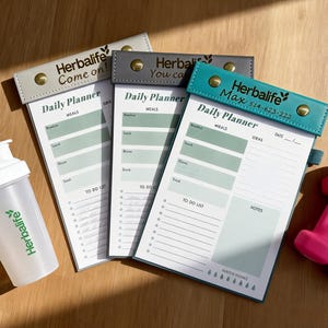 K&ouml;nnte beinhalten: Ein Set aus drei Keramikbechern mit einer gesprenkelten, cremefarbenen Glasur. Jeder Becher hat ein anderes handgemaltes Design: ein blaues und gr&uuml;nes Blatt, eine gelbe Blume und eine rote Beere. Die Becher haben eine einfache, abgerundete Form und einen bequemen Griff.