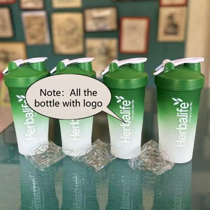 Puede incluir: Cuatro botellas mezcladoras Herbalife verdes y blancas con tapas blancas y un batidor de metal. Las botellas tienen el logotipo de Herbalife y el texto "Live your best life". El texto "Note: All the bottle with logo" est&aacute; en una burbuja.