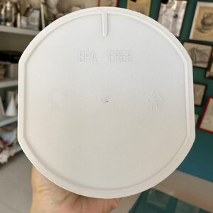 Puede incluir: Tapa de pl&aacute;stico blanco con la inscripci&oacute;n "BPA FREE" y s&iacute;mbolos de reciclaje. La tapa es redonda con un borde ligeramente elevado y una peque&ntilde;a pesta&ntilde;a en la parte superior. Dise&ntilde;ada para un recipiente.