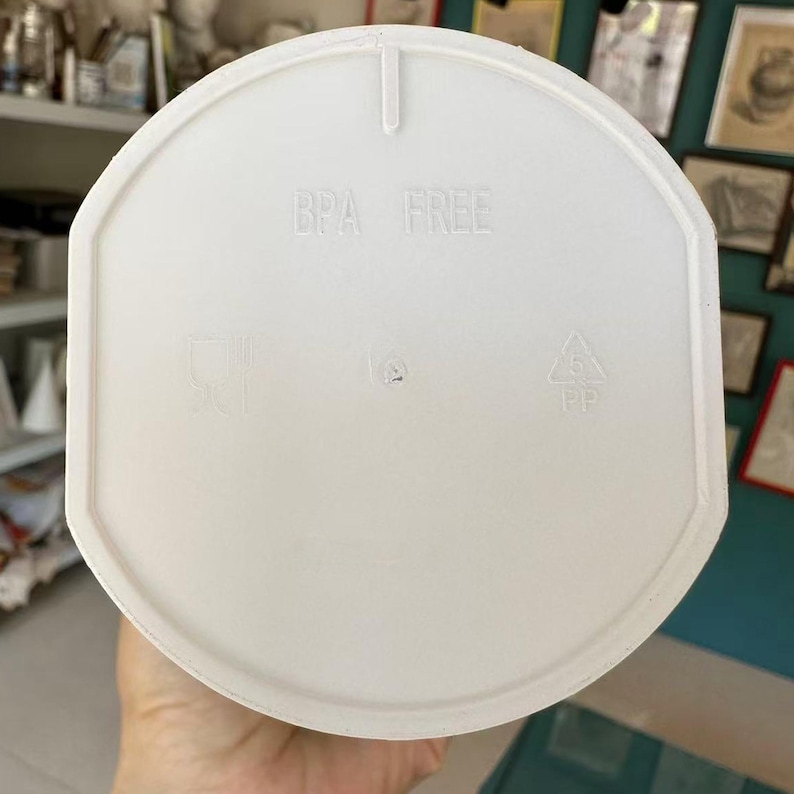 Puede incluir: Tapa de pl&aacute;stico blanco con la inscripci&oacute;n "BPA FREE" y s&iacute;mbolos de reciclaje. La tapa es redonda con un borde ligeramente elevado y una peque&ntilde;a pesta&ntilde;a en la parte superior. Dise&ntilde;ada para un recipiente.