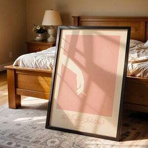 Peut inclure: Une affiche encadr&eacute;e avec un fond rose et une silhouette blanche d'une main tenant une cigarette. L'affiche porte le texte "The Virgin Suicides" en &eacute;criture cursive.