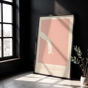 Peut inclure: Une affiche encadr&eacute;e avec un fond rose et une silhouette blanche d'une main tenant une cigarette. Le texte "The Virgin Suicides" est imprim&eacute; en cursive au bas de l'affiche.