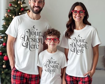 May include: Three people wearing matching white t-shirts with the text "Your Design Here" and red plaid pajama pants. A Christmas tree is visible in the background. The family is smiling at the camera.