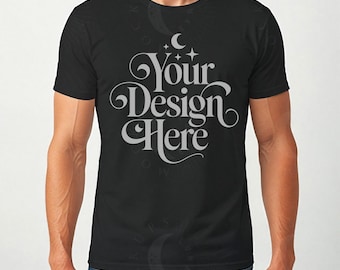 May include: Black crew neck t-shirt with the text "Your Design Here" in a decorative, light gray font. The text is centered on the front of the shirt, with a crescent moon and stars above the text. The shirt is being worn by a person.
