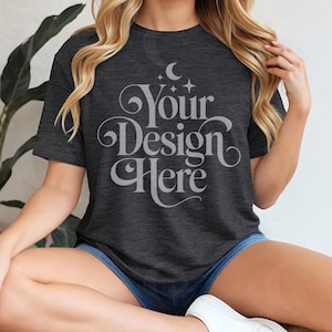 May include: Dark grey t-shirt with the text "Your Design Here" in a decorative font. The shirt is short-sleeved and has a crew neck. The model is wearing blue denim shorts and white trainers.