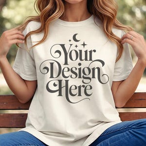 Puede incluir: Una camiseta blanca con un diseño gráfico que dice "Your Design Here" con una luna creciente y estrellas sobre el texto.