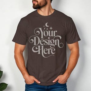 May include: A brown t-shirt with the text "Your Design Here" in a decorative font. The text is in a light gray color.