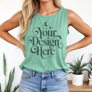 May include: A light green tank top with the text "Your Design Here" in a decorative font. The tank top is sleeveless and has a round neckline. The model is wearing blue denim jeans.
