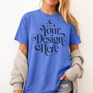 May include: A blue t-shirt with the text "Your Design Here" in a decorative font, featuring a crescent moon and stars. The shirt is short-sleeved and worn with a gray cardigan and denim shorts.