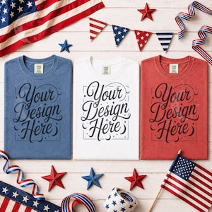 May include: Three t-shirts in blue, white, and red, each with the text "Your Design Here" in a decorative script. The image is decorated with American flags, stars, and patriotic ribbons, suggesting a theme of American pride and design.
