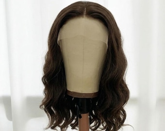 May include: A shoulder-length brown wig with a center part and loose, wavy texture. The wig features a sheer lace front panel that extends across the forehead, designed to mimic a natural hairline, displayed on a beige mannequin head.