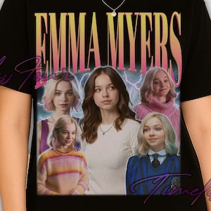 May include: Black t-shirt with the name "EMMA MYERS" in a retro font above a collage of images of a woman. The shirt has a vintage aesthetic, with a faded colour palette and a distressed look. The text "Timeless Four" is also visible.