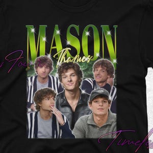 May include: Black t-shirt with a collage of images and the text "MASON Thanos" in a green and yellow gradient. The design includes multiple images of a person. The shirt has a classic crew neck.