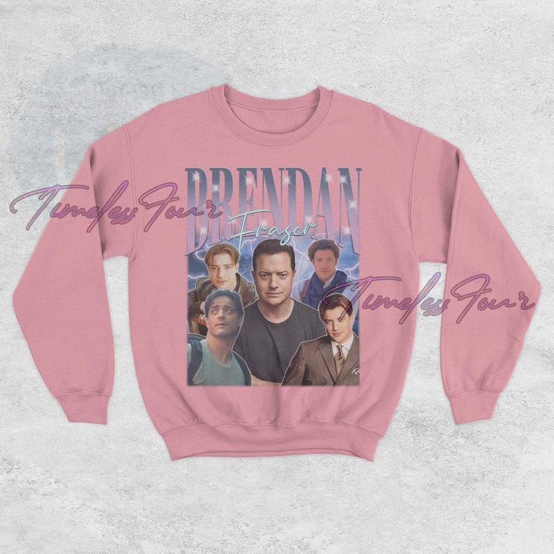 May include: A light pink crewneck sweatshirt featuring a collage of images of Brendan Fraser, with the name "Brendan Fraser" in a vintage font. The design includes a blue and white background.