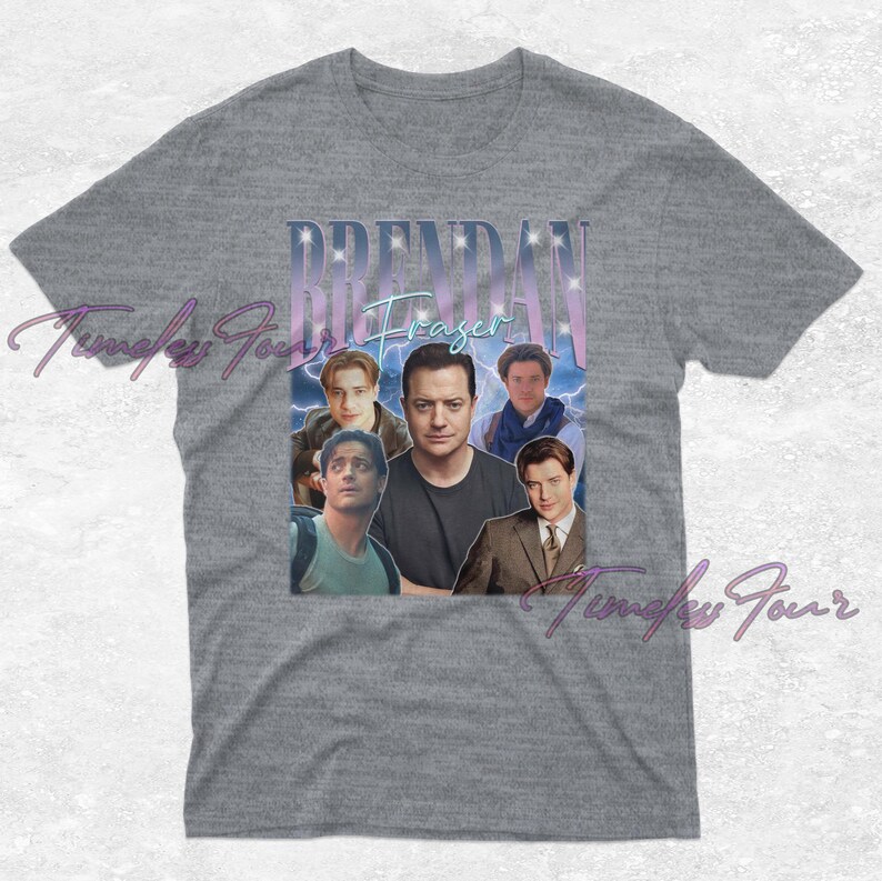 May include: Gray t-shirt featuring a collage of images of actor Brendan Fraser. The design includes the name "Brendan Fraser" in a stylized font with a light blue and purple gradient. The shirt is a classic crew neck.