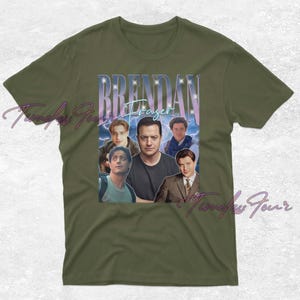 May include: Olive green t-shirt featuring a collage of images of Brendan Fraser with the name "Brendan Fraser" in a stylized font. The design includes multiple images of the actor in various roles, with a vintage aesthetic.