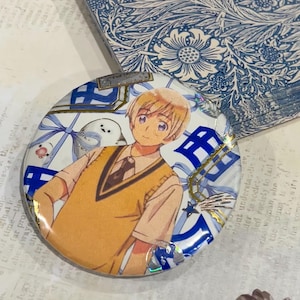 Spilla/distintivo con collage ispirato agli anime finlandesi, realizzata a mano.