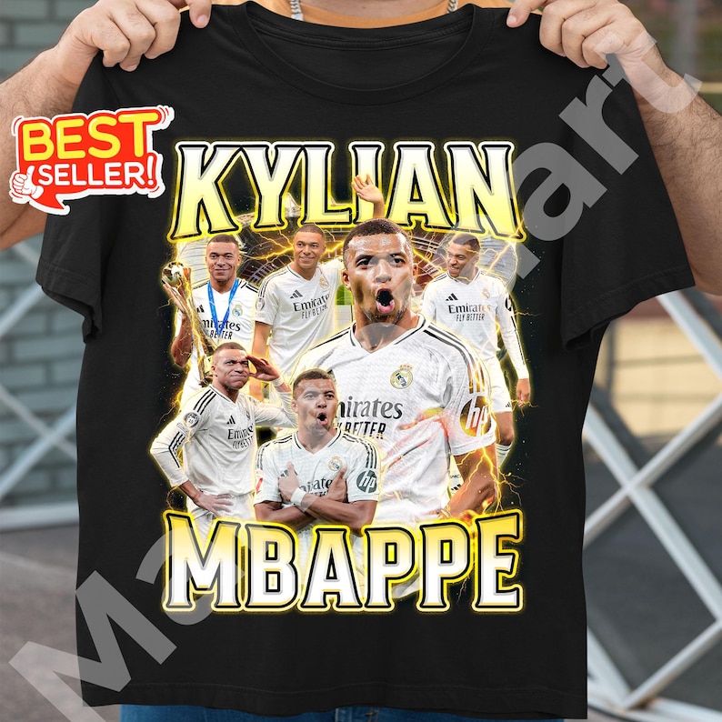 May include: Black t-shirt featuring a graphic of Kylian Mbapp&eacute; in a white soccer jersey. The design includes multiple images of the player, the name "KYLIAN MBAPPE" in yellow, and a "BEST SELLER" sticker.