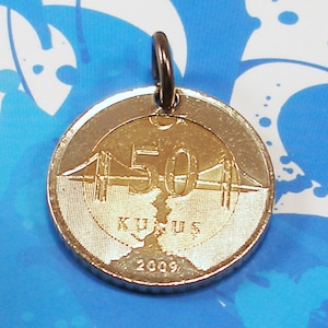 May include: A silver-colored coin pendant with a gold-colored design featuring a bridge and the text "50 KURUŞ 2009".
