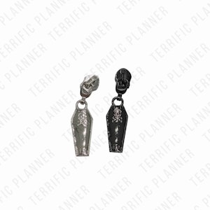 May include: Two zipper pulls in the shape of a coffin. One is silver and the other is black.