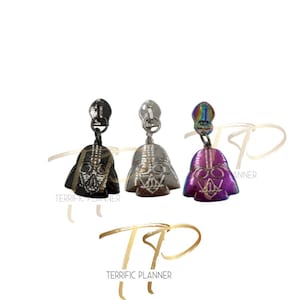 May include: Three zipper pulls featuring a Darth Vader design. The pulls are in black, silver, and iridescent purple.