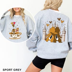 May include: A light gray sweatshirt featuring a cartoon design of Chip and Dale hugging in front of a castle on the back. The front shows Chip and Dale in a teacup with balloons. The text "SPORT GREY" is at the bottom.