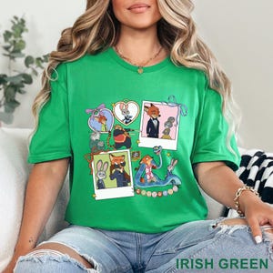 May include: A bright green t-shirt featuring a collage of Zootopia characters in various scenes, including polaroid-style frames, heart-shaped borders, and a blue snake, with the word Zootopia printed in colorful letters at the bottom center.