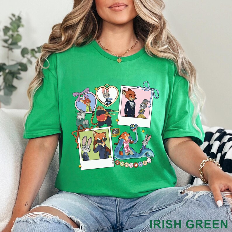May include: A bright green t-shirt featuring a collage of Zootopia characters in various scenes, including polaroid-style frames, heart-shaped borders, and a blue snake, with the word Zootopia printed in colorful letters at the bottom center.