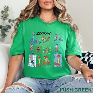 K&ouml;nnte beinhalten: Ein hellgr&uuml;nes Kurzarm-T-Shirt mit einem Grafikdruck verschiedener Zootopia-Figuren in bunten Rahmen. Das Design enth&auml;lt Illustrationen von Judy Hopps und Nick Wilde in verschiedenen Posen, wobei das Wort Zootopia dar&uuml;ber gedruckt ist.