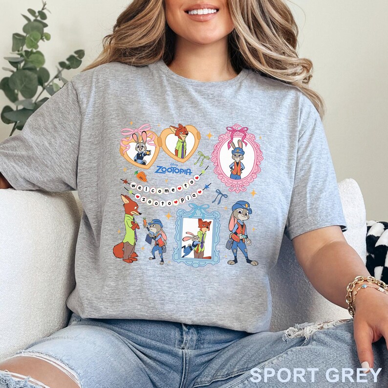 Pode incluir: Camiseta cinza desportiva com um gr&aacute;fico colorido de personagens do filme de anima&ccedil;&atilde;o Zootopia. O design inclui imagens emolduradas dos personagens, a palavra "Zootopia" e a frase "Welcome to Zootopia".