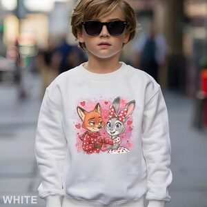 May include: White sweatshirt featuring a cartoon fox and bunny holding a heart-shaped gift box, surrounded by hearts. The fox wears a red scarf, and the bunny has a red bow. The word "WHITE" is printed at the bottom.