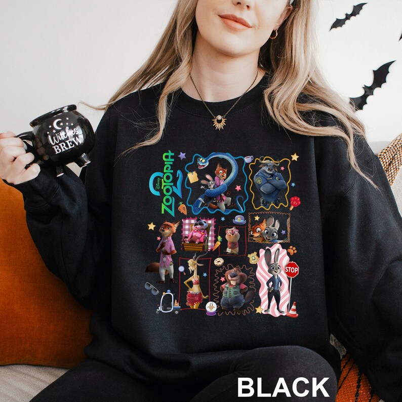 May include: Black crewneck sweatshirt featuring a colorful graphic of characters from the animated film "Zootopia." The design includes the word "Zootopia" in green and the word "BLACK" in white at the bottom.