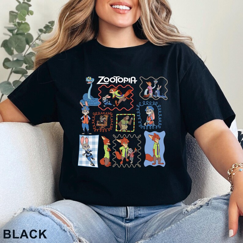 K&ouml;nnte beinhalten: Ein schwarzes Kurzarm-T-Shirt mit einem Grafikdruck verschiedener Zootopia-Figuren in bunten Rahmen. Das Design zeigt Judy Hopps, Nick Wilde und andere Filmfiguren in einer Collage-Anordnung zusammen mit dem Zootopia-Logo-Schriftzug.