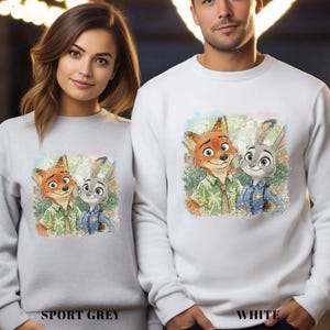 Puede incluir: Sudaderas deportivas grises y blancas con un gr&aacute;fico colorido de Nick Wilde y Judy Hopps de Zootopia. Las sudaderas tienen las palabras "SPORT GREY" y "WHITE" impresas en la parte inferior.