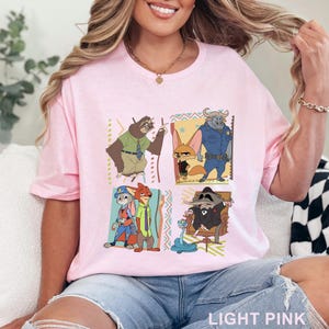 May include: Pale pink t-shirt with a vibrant graphic of Zootopia characters. The design showcases a sloth, fox, buffalo, rabbit, and raccoon. The words "LIGHT PINK" are printed at the bottom of the shirt.