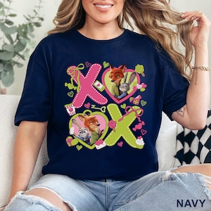 Peut inclure: Un t-shirt bleu marine avec une impression graphique portant le texte XOXO. Le motif comprend des illustrations de Nick Wilde et Judy Hopps de Zootopie dans des c&oelig;urs roses et verts, entour&eacute;s de petites ic&ocirc;nes de c&oelig;urs, cadeaux et bonbons.