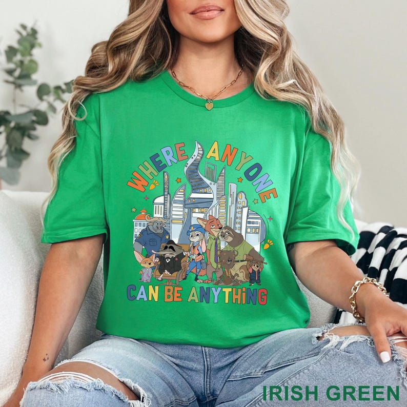 May include: Irish green t-shirt with the text "WHERE ANYONE CAN BE ANYTHING" above a cartoon illustration of various animal characters in front of a city skyline. The shirt is a solid green color.