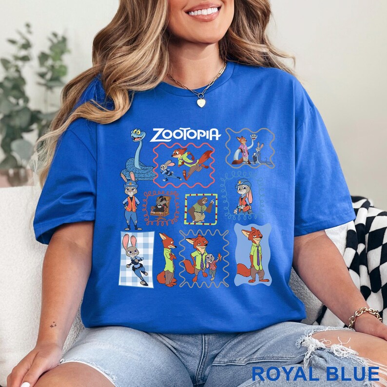 K&ouml;nnte beinhalten: Ein k&ouml;nigsblaues Kurzarm-T-Shirt mit einem Grafikdruck verschiedener Zootopia-Figuren in bunten Rahmen. Das Design enth&auml;lt den Schriftzug Zootopia oben sowie Illustrationen von Judy Hopps, Nick Wilde und weiteren Filmfiguren.