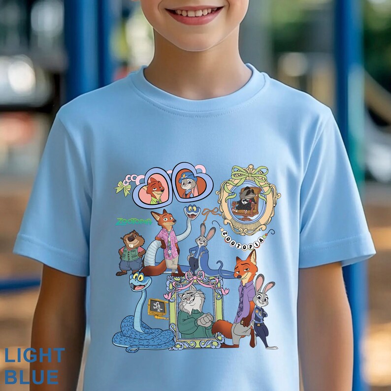 May include: Light blue t-shirt featuring a colorful graphic of characters from the animated movie Zootopia. The design includes images of a fox, rabbit, and other animals, with the word "Zootopia" and "LIGHT BLUE" printed on the shirt.