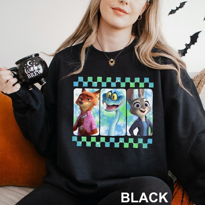 May include: Black sweatshirt with a colourful graphic of three animated characters in a film strip design. The characters include a fox, a snake, and a rabbit. The word "BLACK" is printed at the bottom.