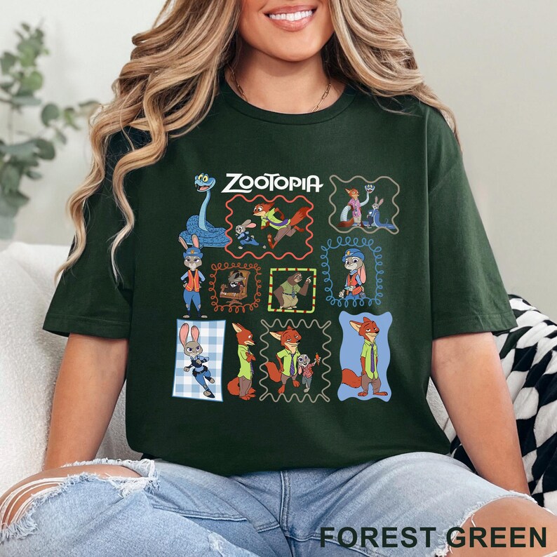 K&ouml;nnte beinhalten: Ein waldgr&uuml;nes Kurzarm-T-Shirt mit einem Grafikdruck verschiedener Charaktere aus dem Film Zoomania. Das Design enth&auml;lt mehrere gerahmte Szenen mit Judy Hopps, Nick Wilde und anderen Charakteren sowie den Schriftzug Zootopia im oberen Bereich.