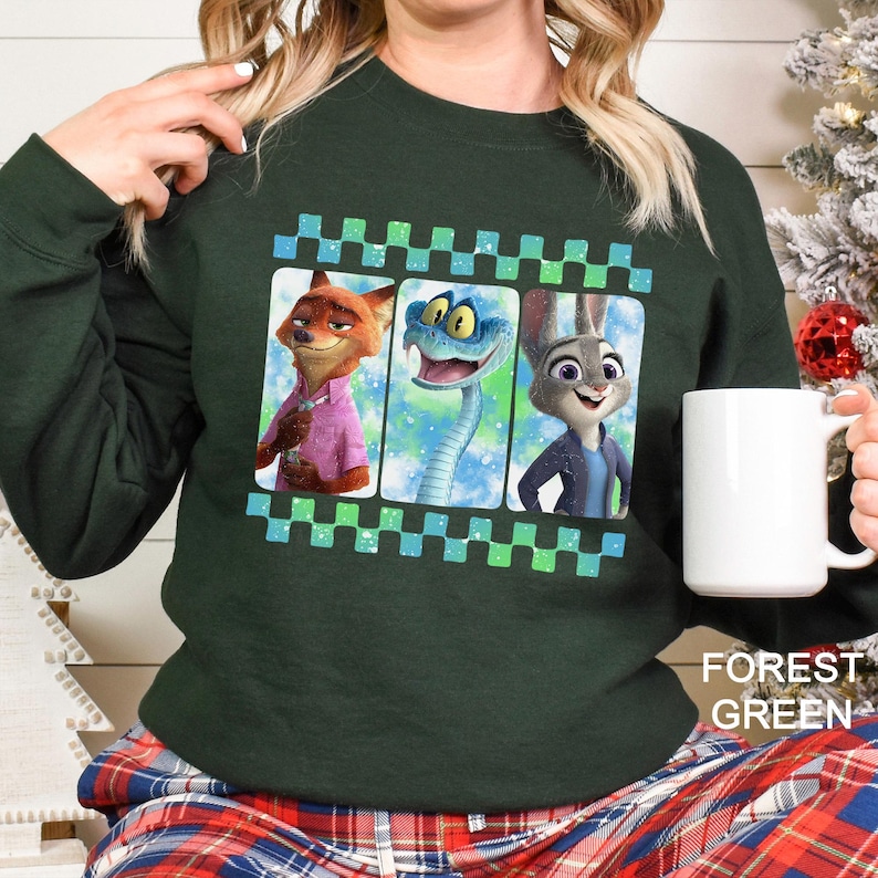 May include: Dark green sweatshirt with a film strip design featuring three cartoon characters: a fox, a snake, and a rabbit. The sweatshirt has a solid color with the words "Forest Green" printed on the bottom right.