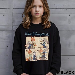 Puede incluir: Sudadera negra con el logotipo de Walt Disney World y una historieta de cuatro paneles de los personajes de Zootopia. La historieta muestra a Nick Wilde y Judy Hopps en varias escenas. La palabra "BLACK" est&aacute; impresa en la esquina inferior derecha.