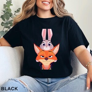 May include: Black t-shirt with a cartoon fox and rabbit design. The fox is orange, the rabbit is grey. The word "BLACK" is printed at the bottom of the image.