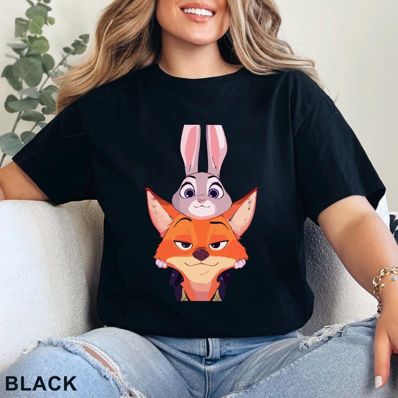 May include: Black t-shirt with a cartoon fox and rabbit design. The fox is orange, the rabbit is grey. The word "BLACK" is printed at the bottom of the image.