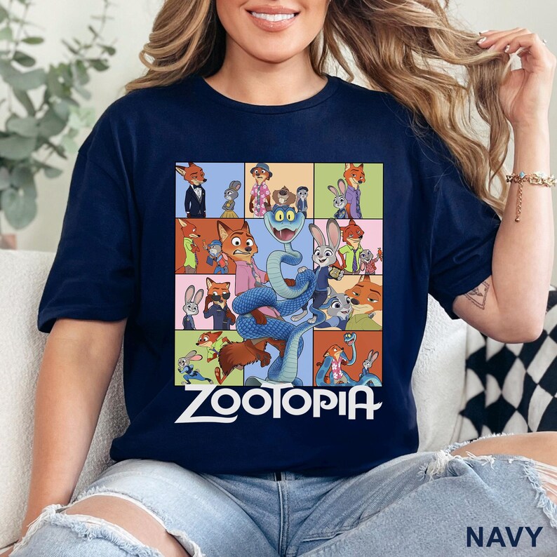 May include: A navy blue t-shirt featuring a grid of various Zootopia character illustrations, including Nick Wilde and Judy Hopps, with a large blue snake in the centre and the white text Zootopia printed prominently at the bottom of the graphic.