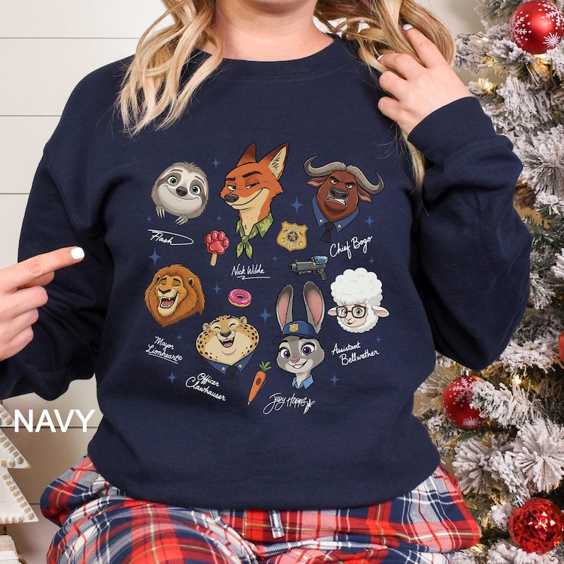 May include: Navy blue sweatshirt with cartoon characters from the film Zootropolis. The design includes Flash, Nick Wilde, Chief Bogo, Mayor Lionheart, Officer Clawhauser, Judy Hopps, and others. The word "NAVY" is printed on the bottom left.
