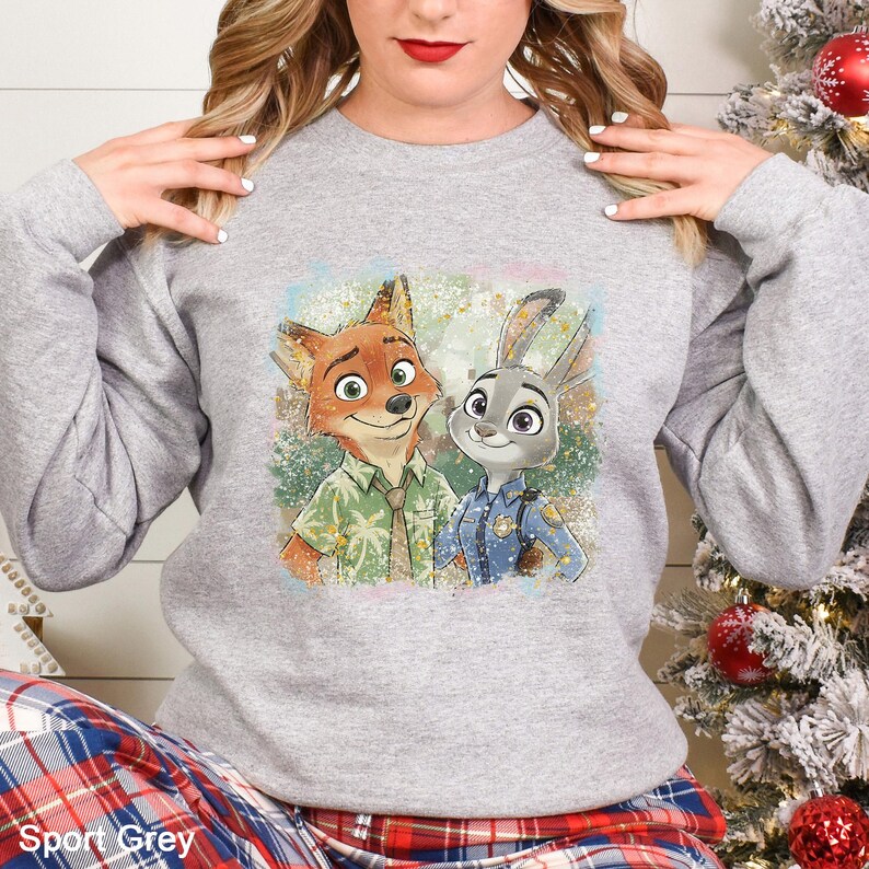 Puede incluir: Sudadera Sport Grey con un gr&aacute;fico colorido de Nick Wilde y Judy Hopps de Zootopia. Nick lleva una camisa verde y Judy un uniforme de polic&iacute;a. La sudadera es de cuello redondo.